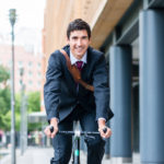 Active young man smiling while riding utility bicycle to his wor